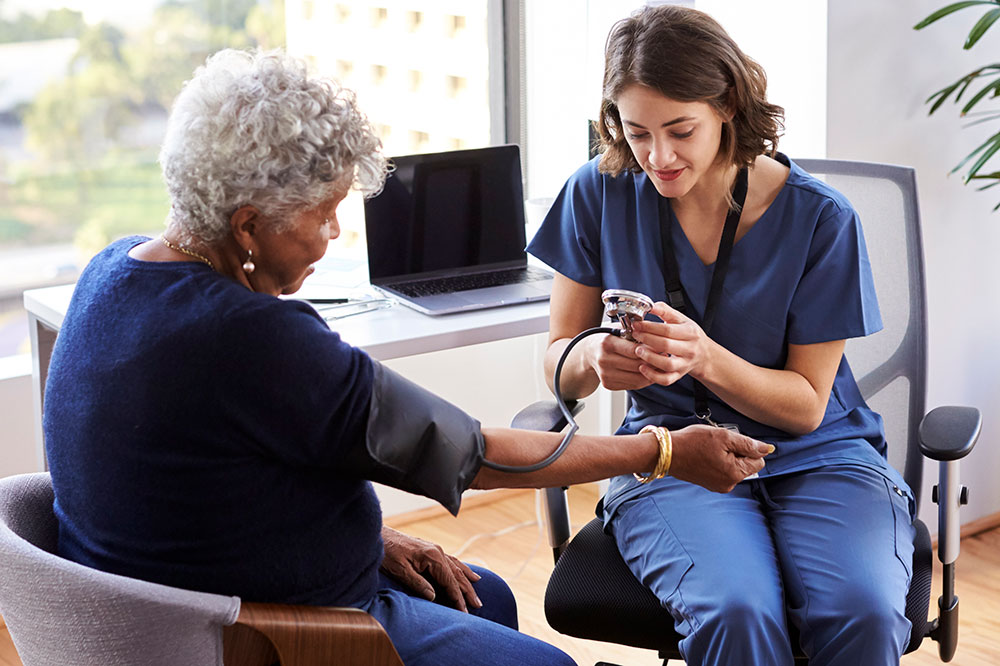 Nurse checking an elderly woman's blood pressure
