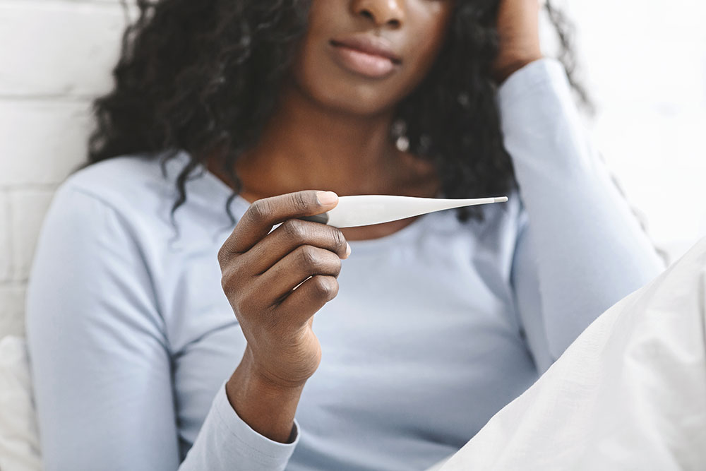 woman checking her temperature with a thermometer